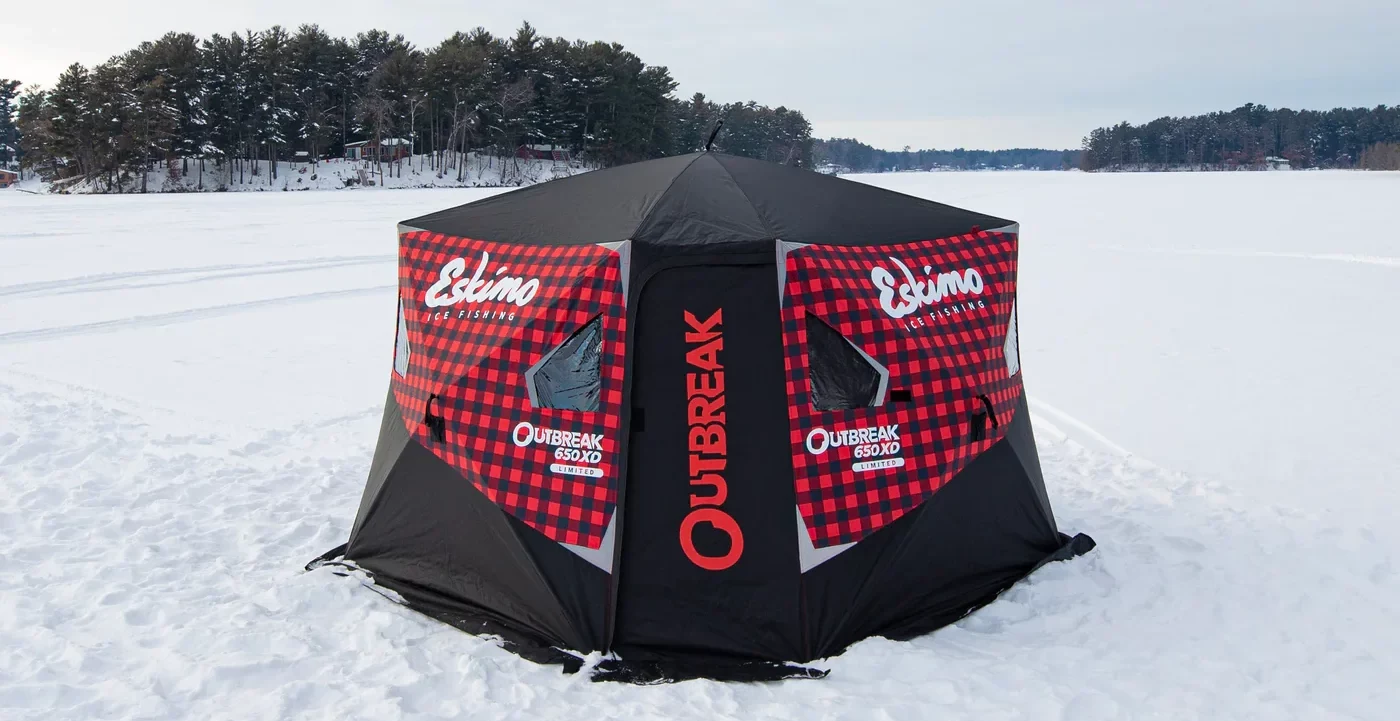 Eskimo ice fishing gear including shelter and auger on frozen lake