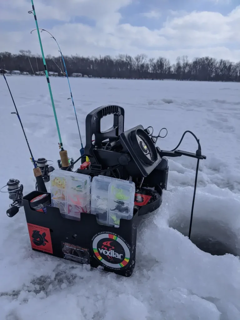 Ice fisherman drilling hole through thick clear ice with hand auger on frozen lake